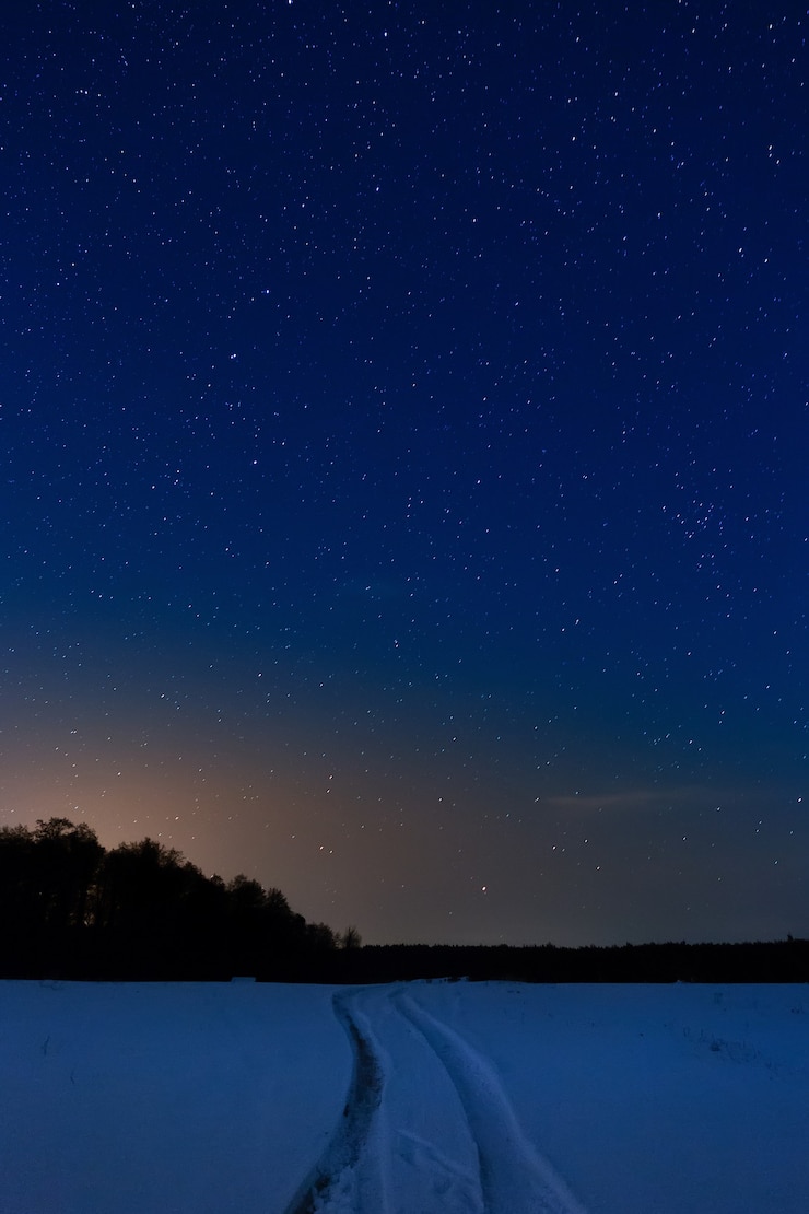 Foto carretera cubierta de nieve en el fondo del cielo nocturno estrellado.