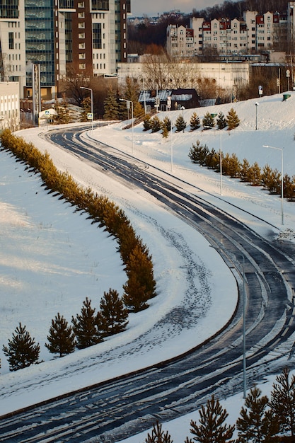 Carretera curva con huellas de neumáticos en la nieve que conduce a un grupo de casas Los árboles crecen a los lados de la carretera Kazan RussiaxA