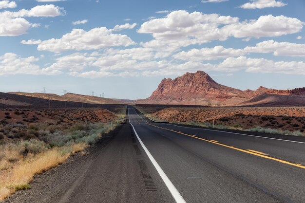 Carretera escénica en el desierto seco con montañas rocosas rojas en segundo plano.