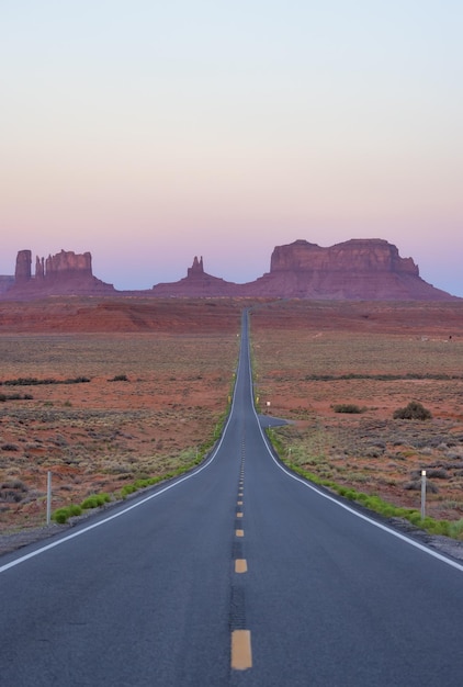 Carretera escénica en el desierto seco con montañas rocosas rojas en segundo plano.