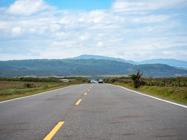 Carretera en Kenting con montañas y costa en el horizonte.