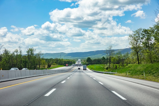 Carretera larga en el fondo azul del cielo nublado del campo americano