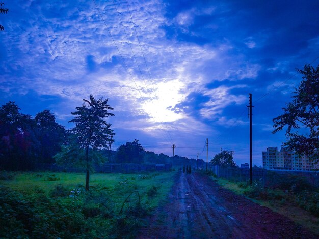 Carretera en medio de árboles en el campo contra el cielo durante la puesta de sol.