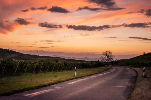 Carretera en medio de un campo contra el cielo durante la puesta de sol