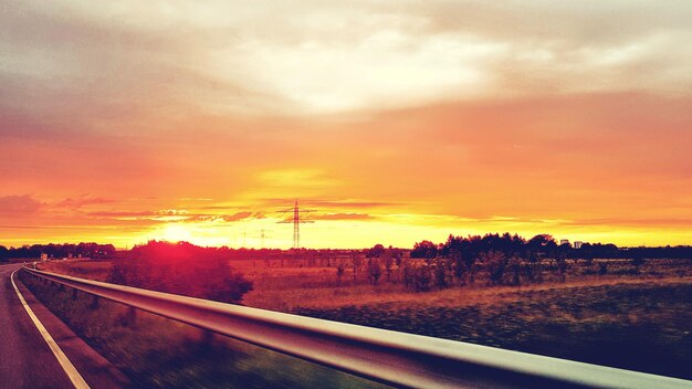 Foto carretera en medio de un campo contra el cielo durante la puesta de sol