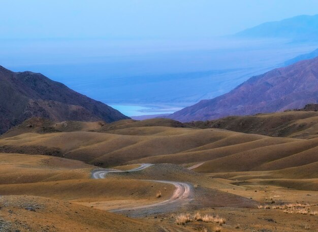 La carretera de montaña desciende entre las colinas de chocolate hasta el lago Paisaje de montaña Embalse de Bartogay y meseta de Assy en Kazajstán cerca de Almaty