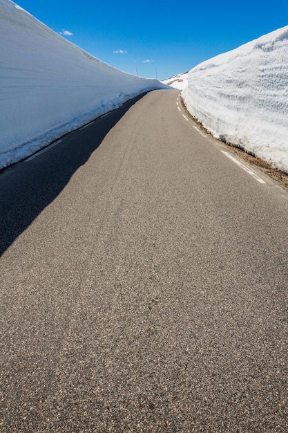 Carretera de montaña en Noruega con un alto muro de nieve