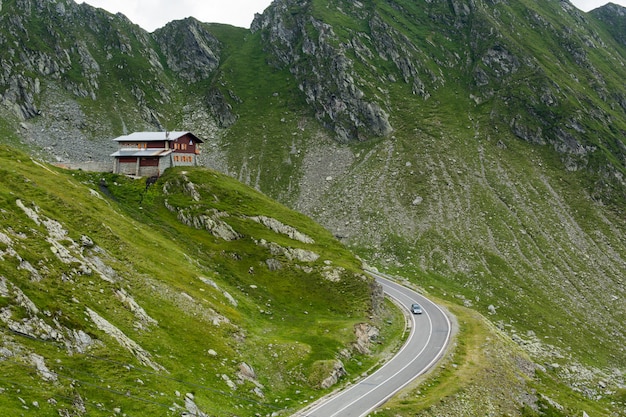 Carretera de montaña Transfagarasan con pequeño edificio en roca, Cárpatos rumanos