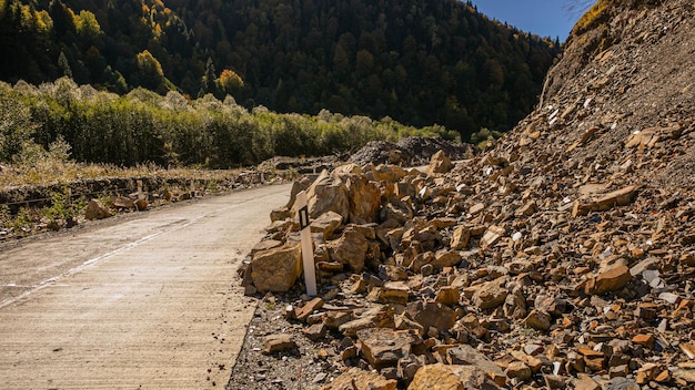 Foto una carretera parcialmente bloqueada por un deslizamiento de rocas en una zona montañosa que representa desastres naturales