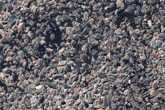 Carretera pavimentada, un primer plano de una parte de la calzada de una carretera asfaltada, una carretera hecha de piedra triturada, resina y otros materiales de construcción