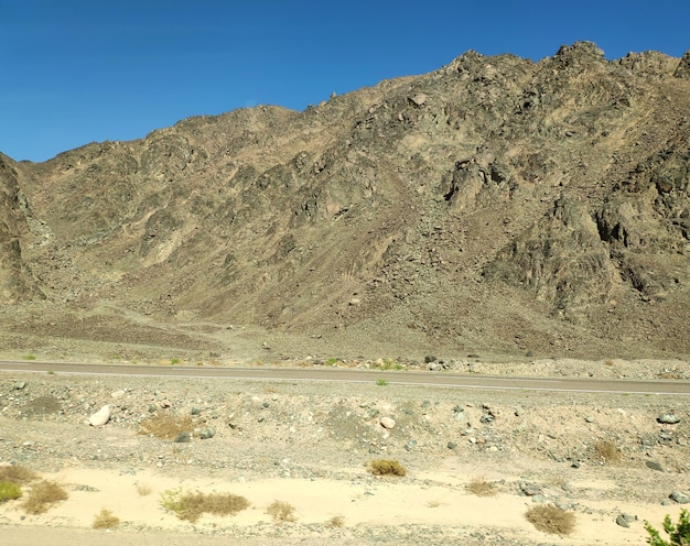 Carretera que atraviesa el desierto del Sinaí pintoresco telón de fondo con montañas y colinas paisaje desértico papel tapiz