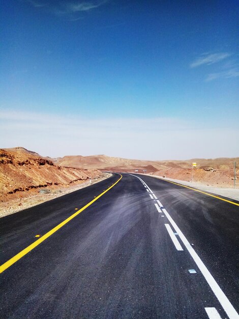 Carretera que pasa por el paisaje contra el cielo azul