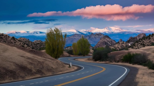 Carretera rodeada de colinas con montañas rocosas cubiertas de nieve