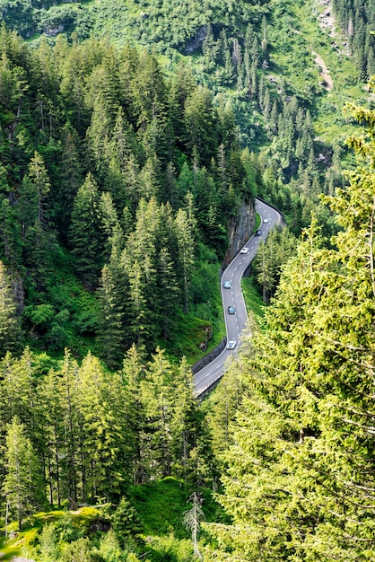 Carretera serpenteante a través de los alpes suizos con coches antiguos