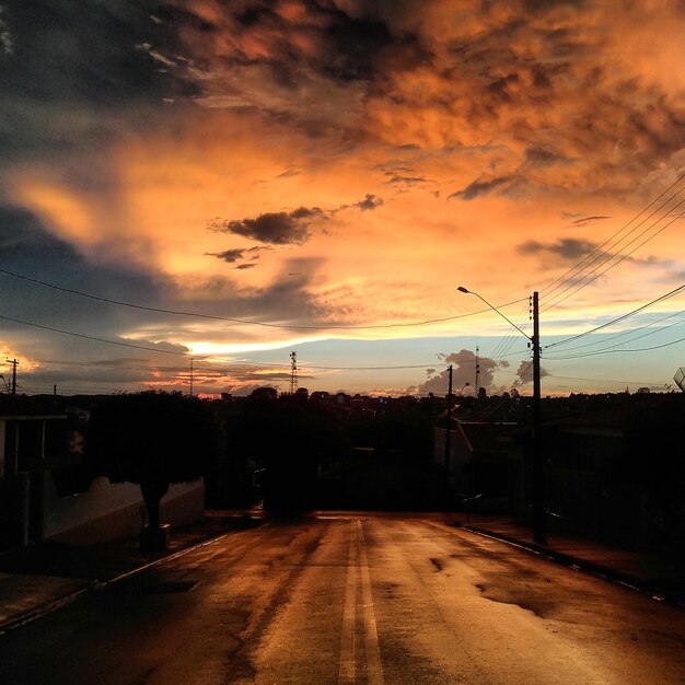 Foto carretera con siluetas de árboles contra el cielo durante la puesta de sol