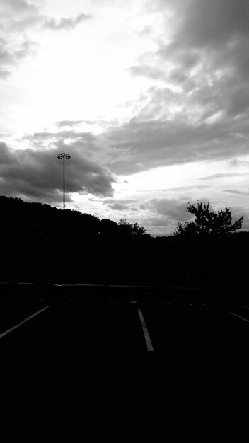 Foto carretera por siluetas de árboles contra el cielo