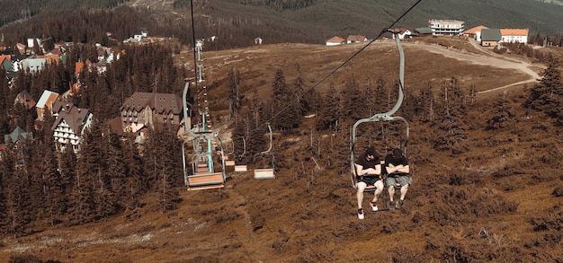 Carretera del teleférico con dos hombres a las montañas en otoño de vacaciones de aventura