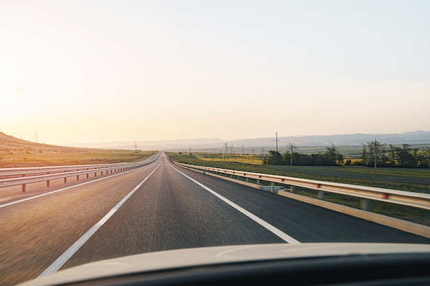 Carretera vacía al amanecer, vista desde la perspectiva del conductor