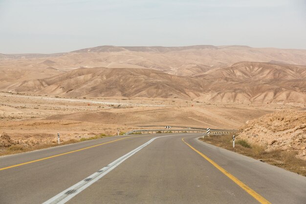 Carretera vacía en algún lugar entre rocas y arenas en el desierto de Negev cerca de Mitzpe Ramon en Israel