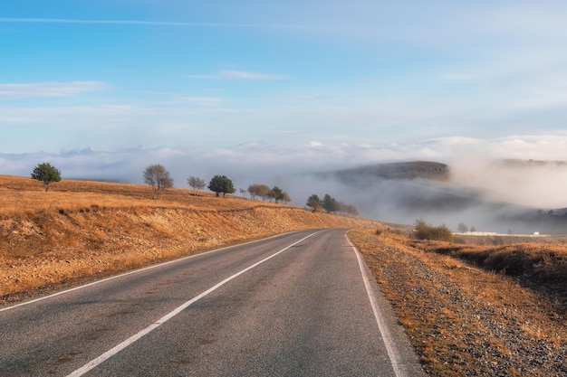 Carretera vacía por la mañana a través del paso en niebla espesa Hermosa autopista de asfalto autopista a través de las colinas de las montañas del paisaje caucásico en clima frío a mediados de octubre