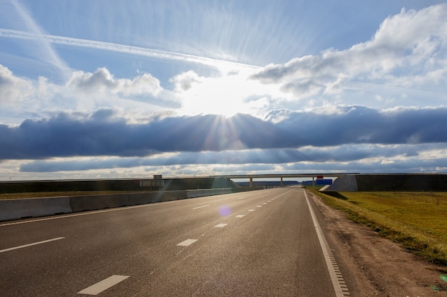 Carretera y viaducto bajo las nubes azules y el sol brillante.