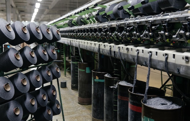 Carretes de hilo de algodón negro en un puesto cerca de la línea de producción