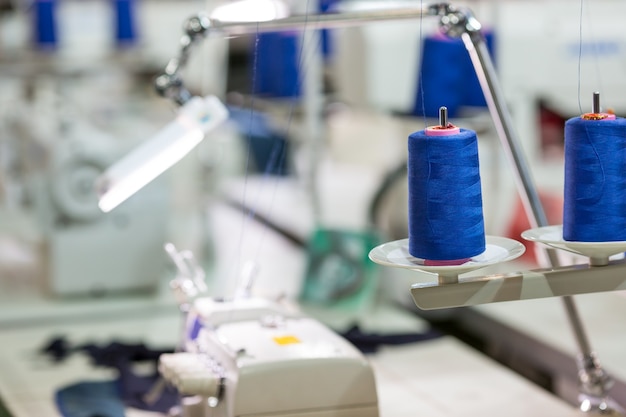 Carretes de hilos azules en la máquina de coser, fábrica