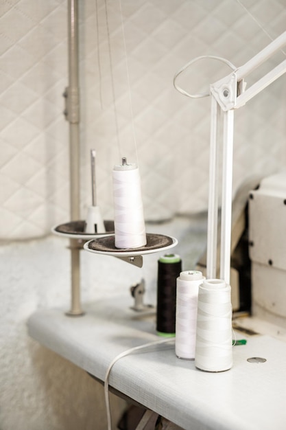 Carretes con hilos blancos para una máquina de coser sobre un soporte en taller