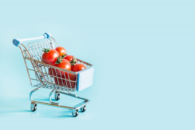 Carretilla de la tienda de comestibles con los tomates en azul.