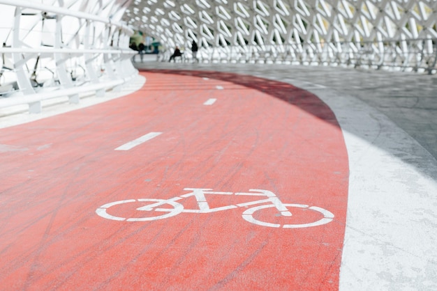 Carril bici en un entorno urbano Primer plano de un cartel de bicicleta pintado sobre una pista de goma roja en el puente