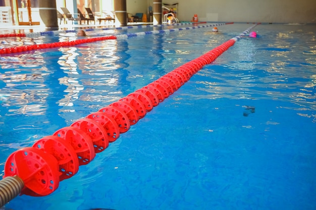 El carril rojo marcado para la preparación de competiciones de natación. Piscina con carriles marcados. Piscina vacía sin gente con agua estancada tranquila. Deportes acuáticos en piscina cubierta, complejo deportivo.