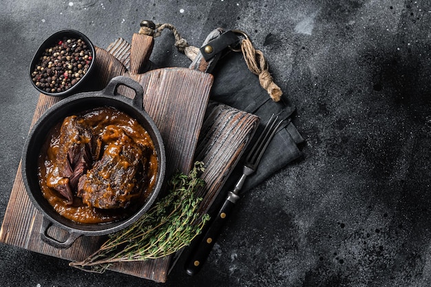 Carrilleras de ternera guisadas con salsa de vino tinto marrón en sartén Fondo negro Vista superior Espacio de copia