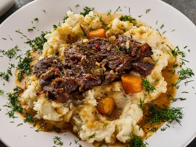 Carrilleras de ternera con puré de patatas en un plato blanco