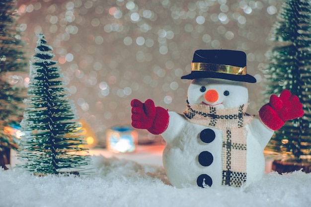 Carrinho de boneco de neve na pilha de neve à noite silenciosa com árvore de Natal e enfeite