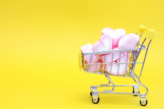 Carrinho de brinquedo do supermercado está cheio de marshmallows em forma de coração