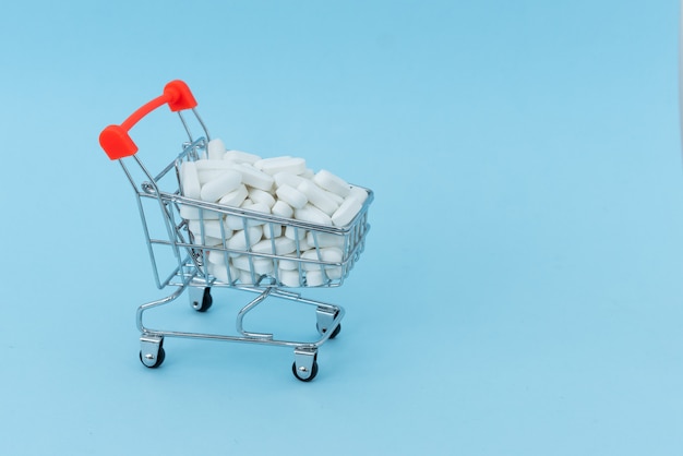 Carrinho de compras cheio de medicamento isolado em azul