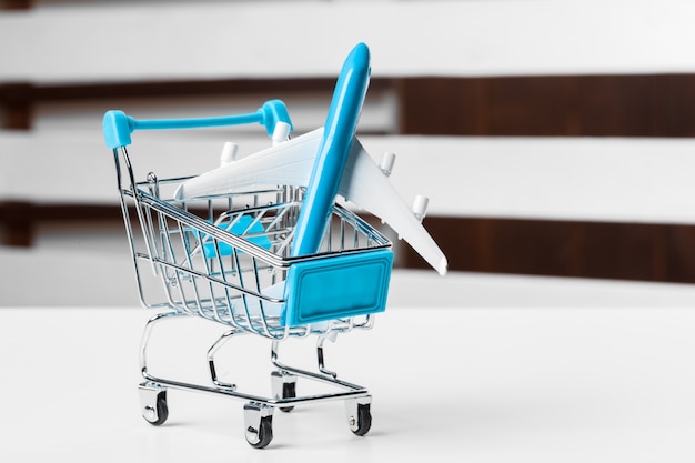 Carrinho de compras com aviões de brinquedo na mesa branca close-up