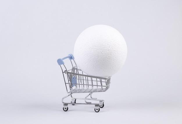 Carrinho de compras com bola no fundo branco