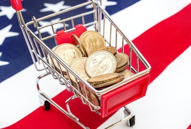 Carrinho de compras com moedas no fundo da bandeira americana