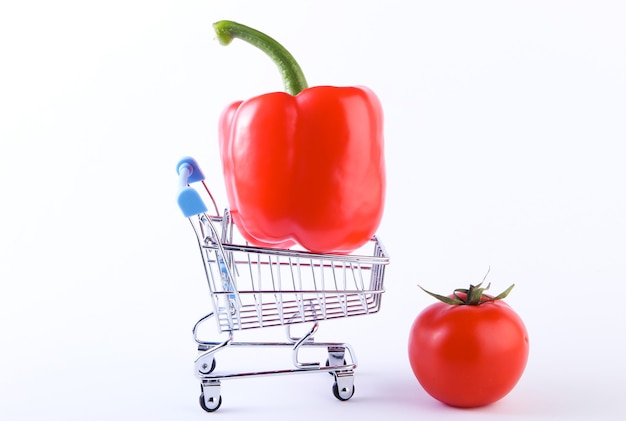 Carrinho de compras com pimentão e tomate em um branco