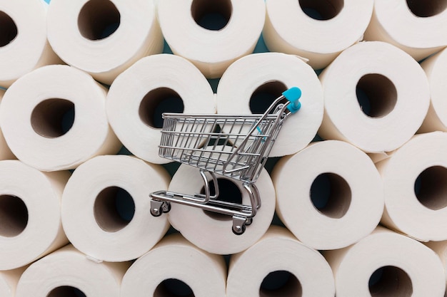 Carrinho de compras de supermercado em um fundo de rolos de papel higiênico