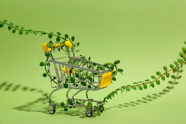 Carrinho de compras entrelaçado com brotos de plantas em fundo verde consumo consciente