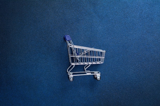 Carrinho de compras vazio em um fundo azul escuro Cesta de compras para produtos