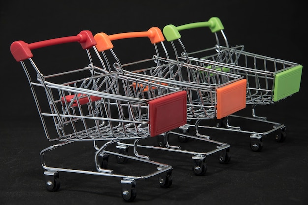 Foto carrinho de compras vermelho, alaranjado, verde em um fundo preto conceito de compra.