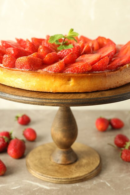 Carrinho de madeira com torta de morango na mesa texturizada cinza.