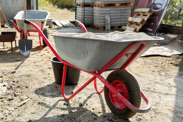Foto carrinho de mão de construção com cimento e uma pá no fundo de uma pilha de telhas cinzentas