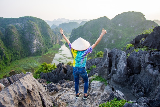 Carrinho de mulher feliz no pico da montanha na caverna de Mua, Ninh Binh, Vietnã, à noite, assunto é turva, baixa chave e ruído.