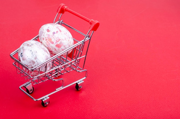 Carrinho de supermercado cheio de ovos de galinha. Conceito de preparação para a Páscoa, comprando comida. Espaço para texto. Foto de estúdio