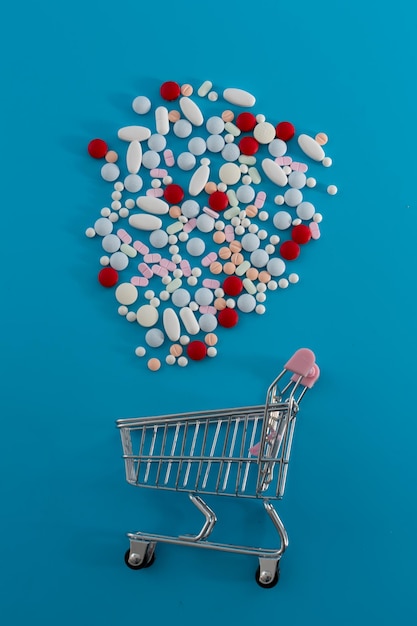 Carrinho de supermercado com comprimidos espalhados em um fundo azul