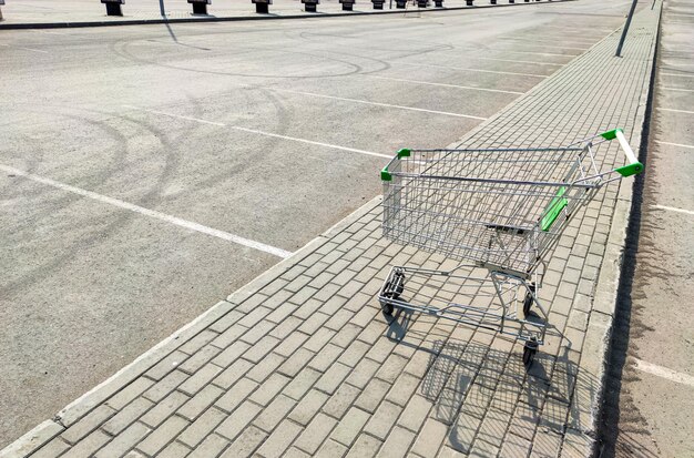 Carrinho de supermercado vazio em um estacionamento vazio perto de um shopping center. Conceito de crise financeira. Problemas de pequenas empresas e vendedores particulares durante a quarentena global devido à pandemia de coronavírus.